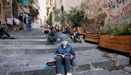 A boy wears a protective mask as Naples school teacher Pamela Buda holds her lessons to her social distancing students on public steps, after the region of Campania closed schools due to a spread of the coronavirus disease (COVID-19) in Naples, Italy, Oct