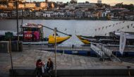 Two women wearing face masks sit at Ribeira in downtown Porto on October 21, 2020. Portugal, which locked down comparatively early to avoid the worst excesses of the first wave of the coronavirus pandemic, has in recent weeks been battling a rising caselo