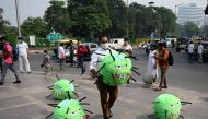 TOPSHOT - An officer from the district magistrate office holds a Covid-19 coronavirus-themed mascot in a market area during an awareness campaign against coronavirus and rising air pollution levels in New Delhi on October 26, 2020. / AFP / Sajjad HUSSAIN