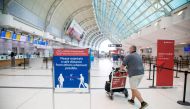 FILE PHOTO: A man pushes a baggage cart wearing a mandatory face mask as a 