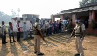 Policemen wearing protective face shields stand guard as voters stand in a queue to cast their vote outside a polling booth during the state assembly election, amidst the spread of the coronavirus disease (COVID-19), at a village on the outskirts of Patna
