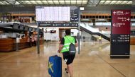 (FILES) This file photo taken on July 30, 2020, shows a volunteer walking in front of the departure information board during a test run at the Berlin-Brandenburg Willy-Brandt international Airport (BER) in Schoenefeld near Berlin.  AFP / Tobias Schwarz 