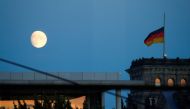 The moon is seen beside the Reichstag, the building which houses the Bundestag (lower house of parliament), from the Chancellery in Berlin before a news conference on new coronavirus restrictions following consultations with the premiers of Germany's 16 f