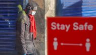 FILE PHOTO: A person wearing a protective mask walks near a social distancing sign, amid the outbreak of the coronavirus disease (COVID-19), in Coventry, Britain October 25, 2020. Reuters/Andrew Couldridge/File Photo