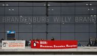 Climate activists hang banners reading 'opening despite climate crisis' (L) and 'BER : Block, Erase, Recycle' in front of the main Terminal of Berlin's airport 