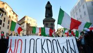 Protestors, wearing masks in the colors of the Italian flag, wave flags and a banner reading 
