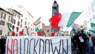 People hold a banner and Italian flags as they protest against the government's restrictive measures imposed to combat the rising number of the coronavirus disease (COVID-19) infections, in Campo De' Fiori, Rome, Italy October 31, 2020. REUTERS/Remo Casil