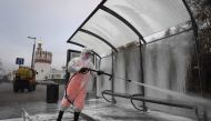 A municipal worker wearing protective equipment sprays disinfectant on a bus stop near the Novodevichy convent in Moscow on November 3, 2020, amid the ongoing coronavirus disease pandemic. / AFP / Natalia KOLESNIKOVA