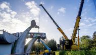 TOPSHOT - Workers use a crane to the salvage a metro train after it overran a barrier at De Akkers station in Spijkenisse on November 3, 2020. and ended up suspended on a work of art in the shape of a large whale's tail. / AFP / ROBINUTRECHT / ANP / Robin