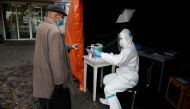 FILE PHOTO: A health worker in a protective suit gives a document to man, amid the coronavirus disease (COVID-19) outbreak, at a test center in front of a hospital in Warsaw, Poland October 27, 2020. REUTERS/Kacper Pempel/File Photo
