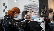 A hairdresser is seen cutting a clients hair while wearing protective face masks in Hensmans hair salon, after new nationwide restrictions were announced during the coronavirus disease (COVID-19) outbreak in Milton Keynes, Britain, November 4, 2020. (REUT