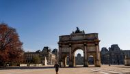 A jogger runs in front of Arc de Triomphe du Carrousel in Paris on November 6, 2020, during a lockdown imposed by authorities in an attempt to halt the spread of the new coronavirus (Covid-19). AFP / Ludovic Marin 