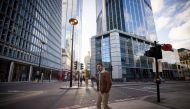 A man wearing a protective face covering to combat the coronavirus walks along a quiet street in the City of London on November 10, 2020.  / AFP / Tolga Akmen
