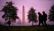 People walk past the Washington monument at sunset in Washington, U.S., November 12, 2020. REUTERS/Hannah McKay
