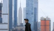 A person wearing a face mask walks in Weehawken, New Jersey, on November 11, 2020, with the New York skyline in the background. Mayor Bill de Blasio said November 9 that New York City is getting “dangerously close” to a second coronavirus wave as the infe