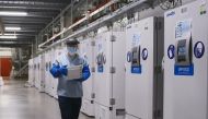 A worker passes a line of freezers holding coronavirus disease (COVID-19) vaccine candidate BNT162b2 at a Pfizer facility in Puurs, Belgium in an undated photograph. Pfizer/Handout via Reuters