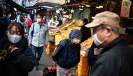 An elderly woman walks though an alley at a market in Tokyo's Tsukiji area on November 21, 2020. / AFP / Charly TRIBALLEAU