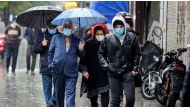 Pedestrians, clad in mask due to the COVID-19 coronavirus pandemic, walk in the rain past closed shops along a street in Iran's capital Tehran on November 21, 2020, as the Iranian government announced new pandemic-countering measures. / AFP / -
