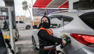 Salma al-Najjar, a 16-year-old Palestinian who works at a petrol station to help her family with income, refuels a car in Khan Yunis in southern Gaza Strip, 24 November 2020. / AFP / SAID KHATIB