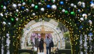People wearing masks to prevent the spread of COVID-19 walk through a holiday season and Christmas outdoor display in Beverly Hills, California, November 23, 2020. / AFP / Robyn Beck
