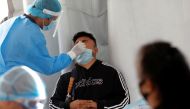 A healthcare worker wearing personal protective equipment (PPE) takes a swab sample from a man for coronavirus disease (COVID-19) rapid antigen testing outside the Azteca stadium in Mexico City, Mexico, November 25, 2020. REUTERS/Henry Romero
