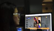 (FILES) In this file photo, a journalist follows the live online encounter between Colombian President Ivan Duque (top) and Venezuelan opposition leader and self-declared acting president Juan Guaido, on a computer in Caracas, on February 15, 2019. AFP / 
