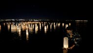 A woman sets afloat lanterns on the water during the Japanese ceremony 