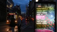 Pedestrians stand near a COVID-19 information board in Hull, in north-east England on November 30, 2020. Hull will return to the England's highest coronavirus category, Tier 3, when England exits its second lockdown an re-enters a tiered system of toughen