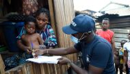 Bidemi Aye receives a pre-paid debt card for cash and food provided by World Food Programme (WFP) in a makeshift home in the Makoko riverine slum settlement in Lagos on November 27, 2020.  AFP / PIUS UTOMI EKPEI
