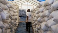 World Food Programme employee walks between sacks of food at the Um Rakuba refugee camp which houses Ethiopian refugees fleeing the fighting in the Tigray region, on the Sudan-Ethiopia border in Sudan, November 29, 2020. REUTERS/Baz Ratner
