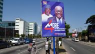 Street vendors walk past campaign posters of Ghanian President and candidate of the ruling New Patriotic Party (NPP) Nana Akufo-Addo and his running mate, Mahamudu Bawumia, in Accra, on December 4, 2020.  AFP / PIUS UTOMI EKPEI