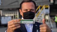 Sao Paulo Governor Joao Doria shows to members of the media a package of the CoronaVac vaccine as containers carrying doses of it are unloaded from a cargo plane that arrived from China at Guarulhos International Airport in Guarulhos, near Sao Paulo, Braz