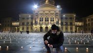 A man lights candles symbolizing the coronavirus disease (COVID-19) victims during a candlelight vigil on the Bundesplatz, in front of the seat of the Swiss federal parliament, Bundeshaus, in Bern, Switzerland December 6, 2020. Picture taken December 6, 2
