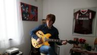Javier Parisi, who impersonates late former Beatle John Lennon, plays the guitar during an interview with Reuters, in Lanus, on the outskirts of Buenos Aires, Argentina November 18, 2020. Picture taken November 18, 2020. REUTERS/Agustin Marcarian