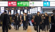 Commuters wearing face masks walk along a concourse at Shinagawa station in Tokyo on December 10, 2020. / AFP / Kazuhiro NOGI