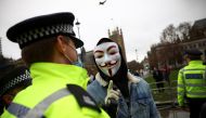 A person wearing mask talks with a police officer during an anti-vaccination demonstration at Parliament Square in London, Britain, December 14, 2020. REUTERS/Henry Nicholls