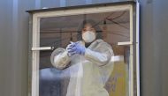 A medical staff member wearing protective gear waits in a booth for visitors to take samples for the Covid-19 coronavirus test at a temporary testing station outside a railway station in Seoul on December 16, 2020 as South Korea ramps up coronavirus check