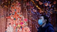  A pedestrian wearing a face mask or covering due to the COVID-19 pandemic, walks past a Christmas-themed display in a shop window on Oxford Street in central London on December 22, 2020.  AFP / Tolga Akmen