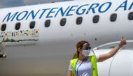 In this file photograph taken on June 12, 2020, an airport official gestures while standing in front of an aircraft of national airline Montenegro Airlines at Podgorica Airport, as the carrier recommenced flights which were halted due to the spread of the