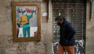 A man walks past a new work by Italian street artist TvBoy depicting Santa Claus carrying the Covid-19 vaccine in his sack, in Barcelona on December 24, 2020.   / AFP / Josep LAGO