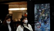 File photo: Women wearing protective masks amid the coronavirus disease (COVID-19) outbreak walk past a poster for an animated movie 