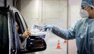 A car driver receives a self-test kit as he must answers questions to the medical staff, at a Covid-19 test location in Tilburg, on December 23, 2020. - Netherlands OUT / AFP / ANP / Koen van Weel