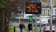 People walk past a roadside public health information sign, amidst the coronavirus disease (COVID-19) pandemic, in London, Britain, December 29, 2020. REUTERS/Toby Melville
