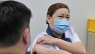 This handout photo taken and released on December 30, 2020 by Singapore's Ministry of Communications and Information shows the COVID-19 coronavirus vaccine being given to senior staff nurse Sarah Lim (R) as Singapore began its vaccination exercise with th
