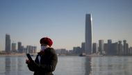 A woman uses her mobile phone along the banks of the Yangtze River on New Year's Eve day in Wuhan in China’s central Hubei province on December 31, 2020. / AFP / Noel Celis