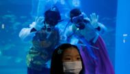 A girl wearing a mask poses for photographs in front of divers in Korean traditional costumes 