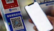 Customer uses a phone to scan the QR code of the electronic payment service alipay that belongs to Ant Group Co Ltd at a market stall in Beijing, China, December 31, 2020. REUTERS/Thomas Peter
