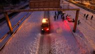 An emergency vehicle drives past people walking in the snow on the M-30 motorway, in Madrid, Spain, January 9, 2021. REUTERS/Susana Vera
