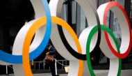 A man wearing a protective mask against COVID-19 is seen through the Olympic rings in Tokyo, Japan January 8, 2021. REUTERS/Issei Kato/File Photo