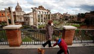A woman wearing a protective face mask walks her dog near the Roman Forum, one day before the country goes back to lockdown as part of the efforts put in place to curb the spread of the coronavirus disease (COVID-19), in Rome, Italy, January 4, 2021. REUT
